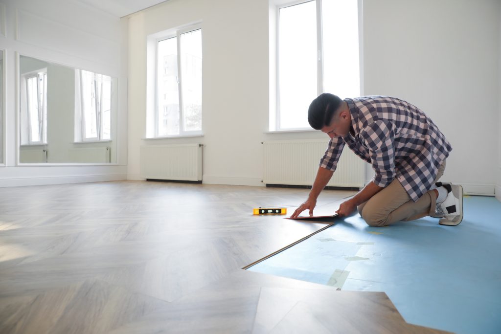 Professional worker installing new parquet flooring indoors