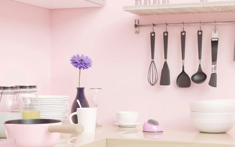 a pink kitchen with utensils hanging on the wall