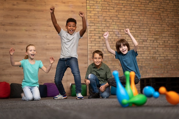 Full shot smiley kids playing bowling